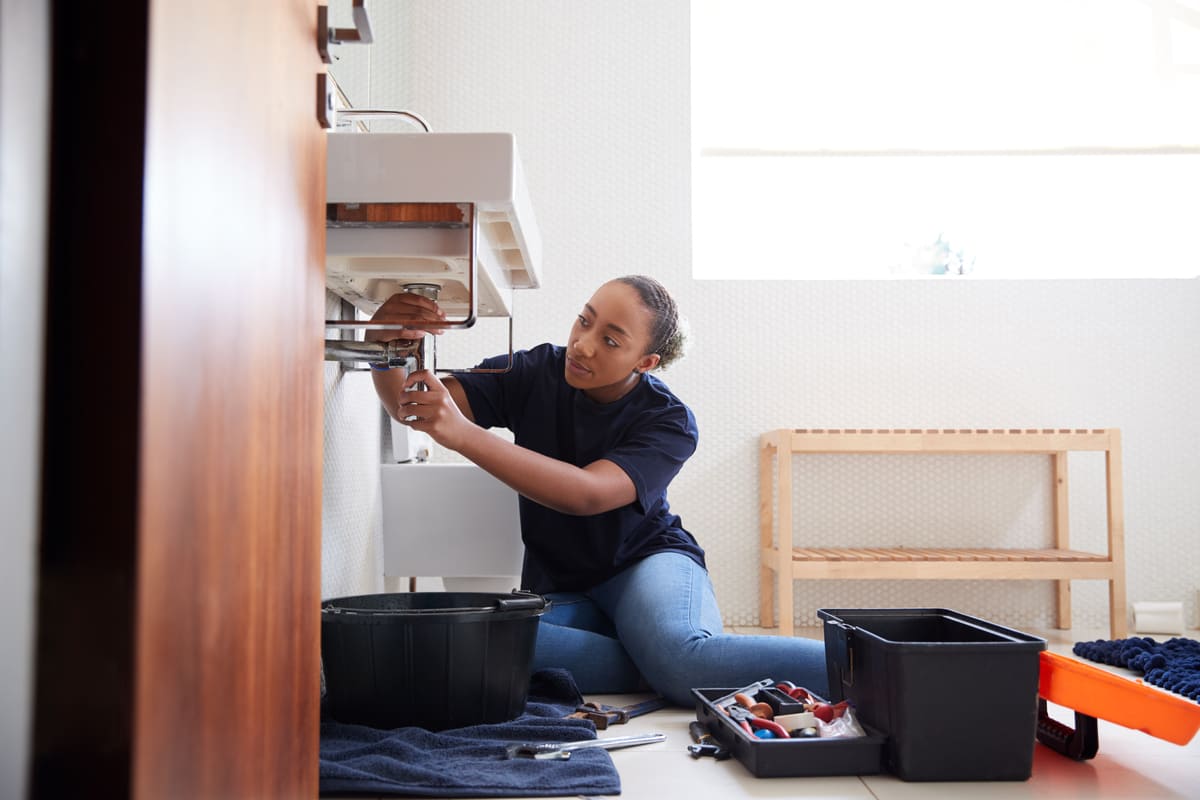 A woman fixing a sink in a home