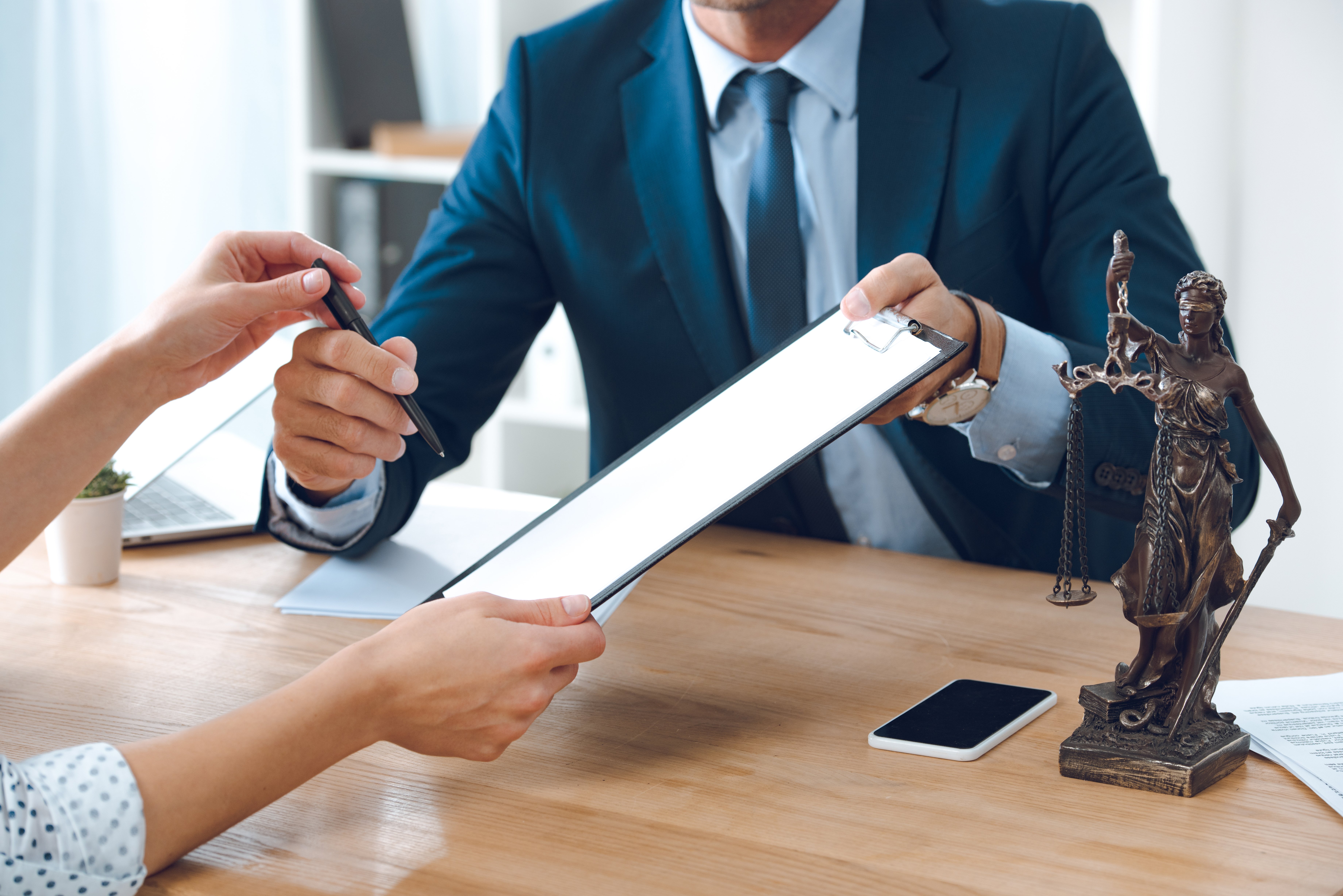 Cropped shot of lawyer giving clipboard and pen to young woman in office