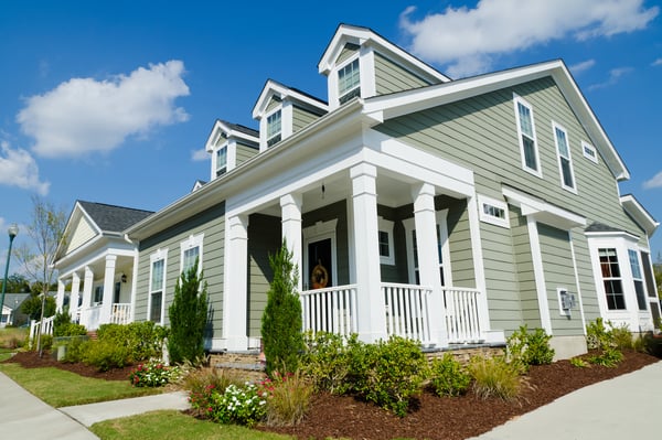 A greenish house with white trim and columns