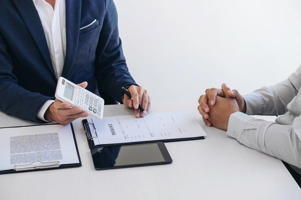 Two people are going over forms with a calculator