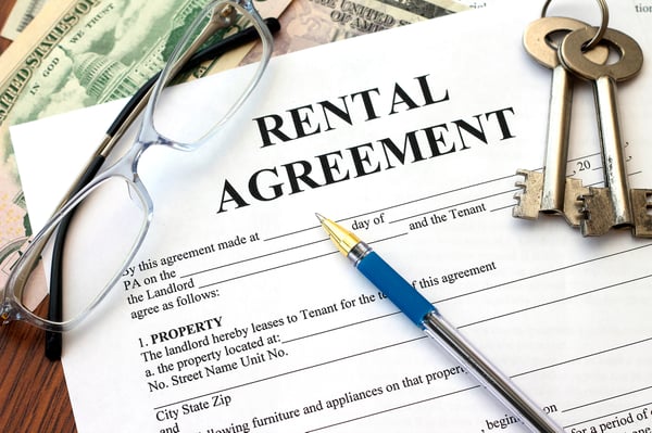 A rental agreement form with glasses, keys, a pen, and cash