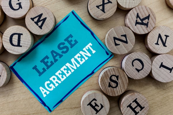 A blue card with "Lease Agreement" on it surrounded by round, wooden letter.