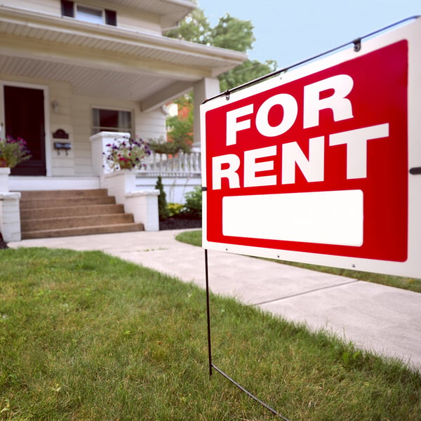 A house with a 'for rent' sign in front