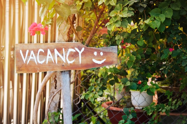 Wood sign with 'VACANCY' and a smiley face painted on it.