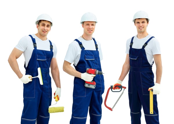 Three men in hardhats and overalls holding tools