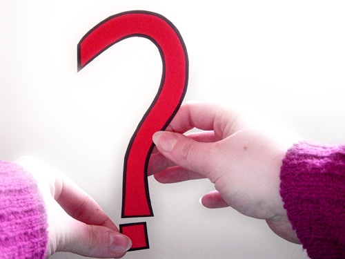 person holding a red question mark cutout 
