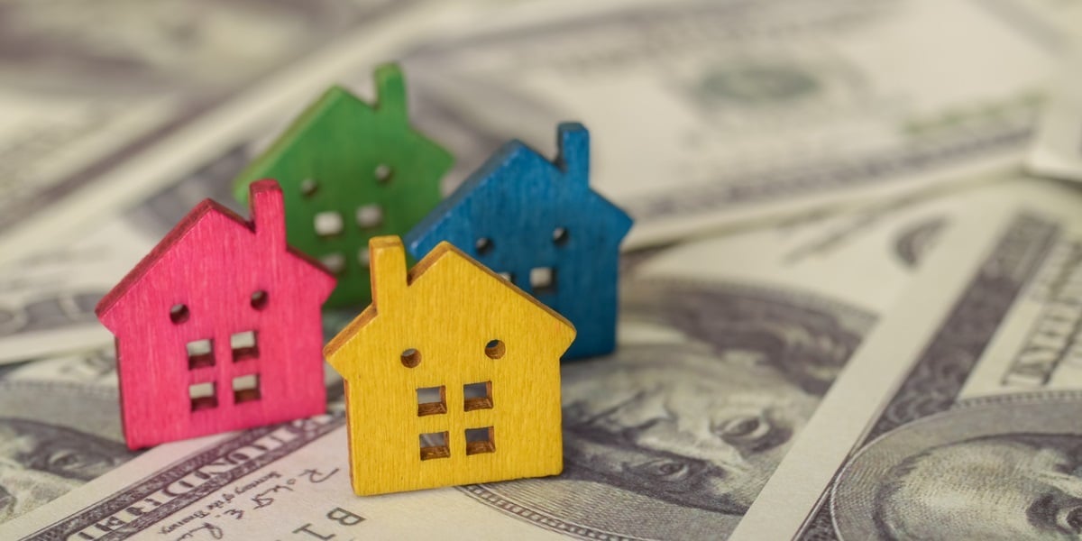 Wooden houses on top of $100 bills