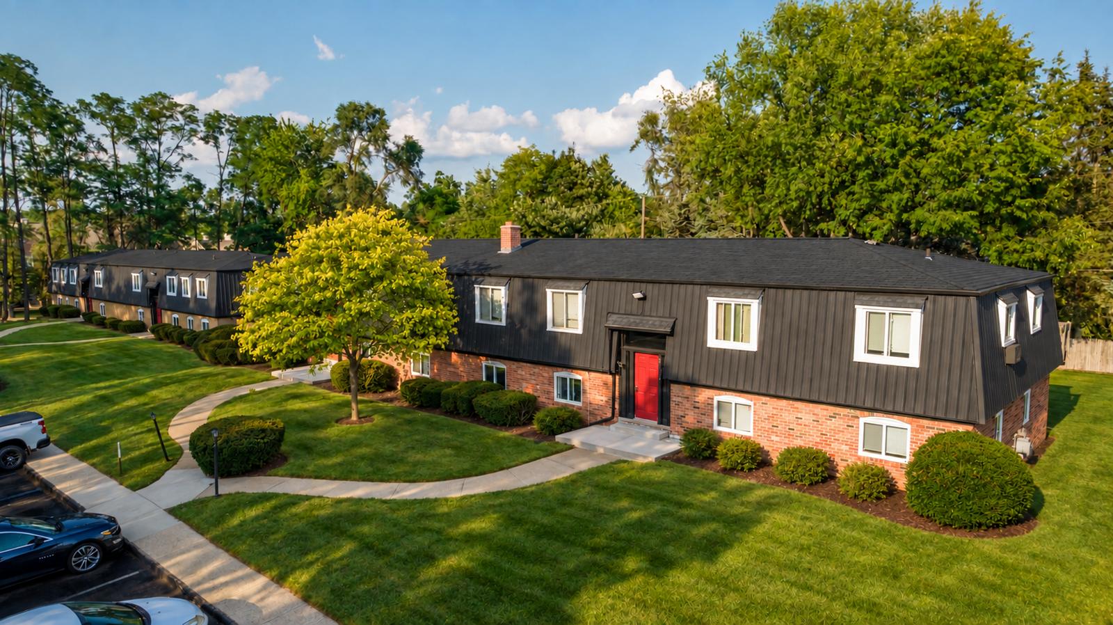 Aerial view of Z on Decker brick buildings with black standing-seam upper floors, red entry doors, curved walkways and mature trees