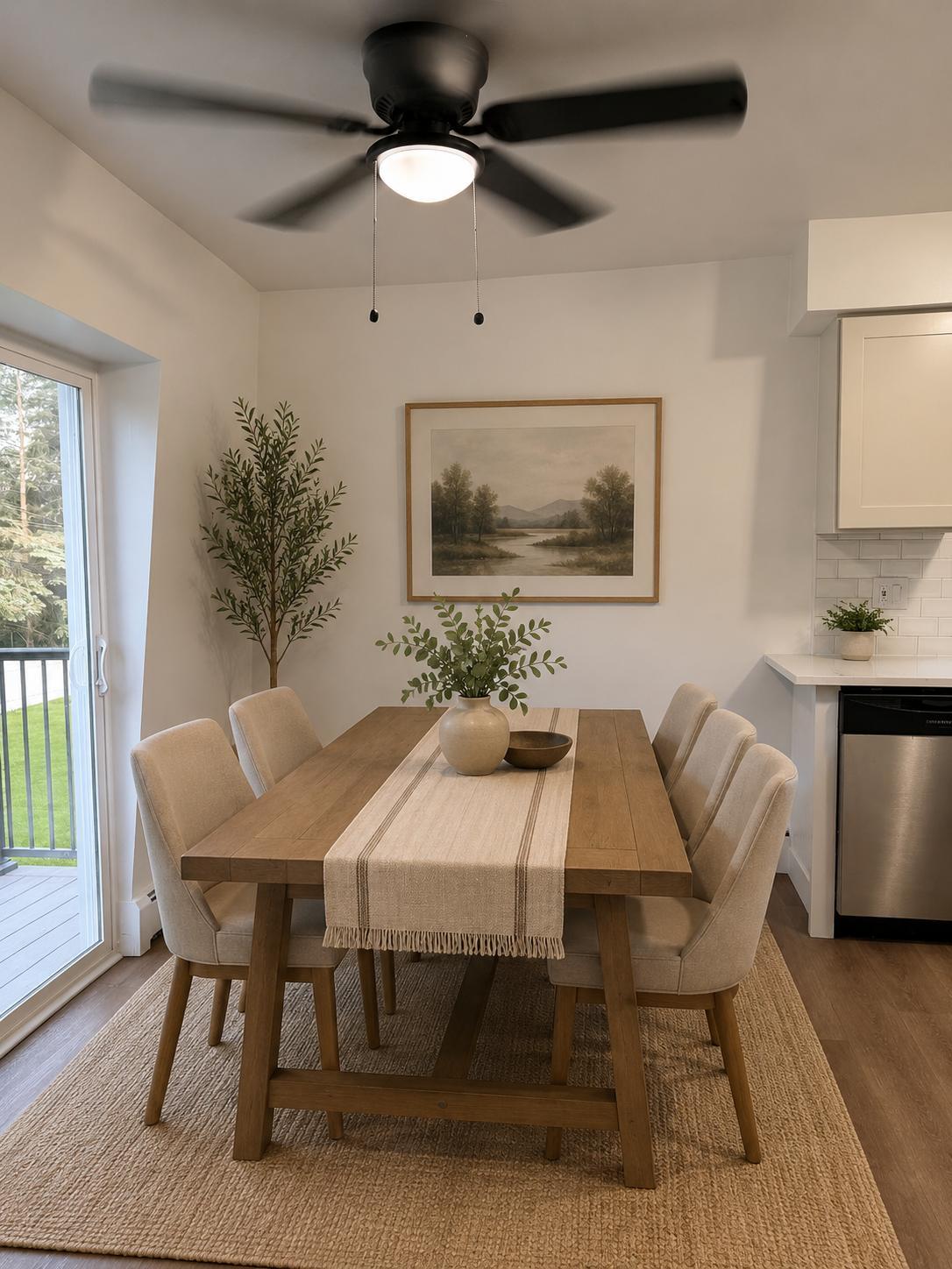 Dining area with a farmhouse table, ceiling fan and a sliding door to the private deck