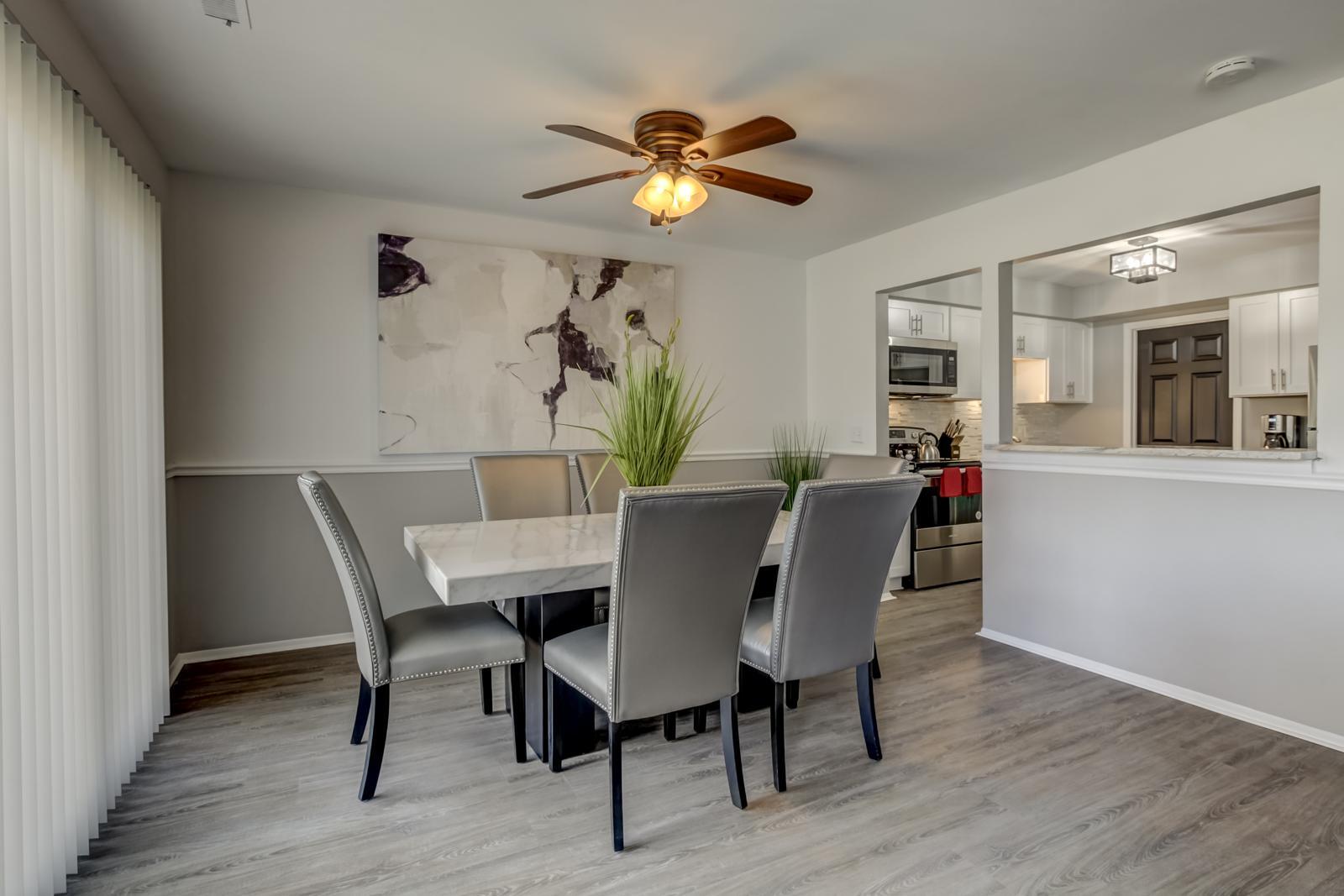 Dining area with a marble-top table and a pass-through to the white kitchen