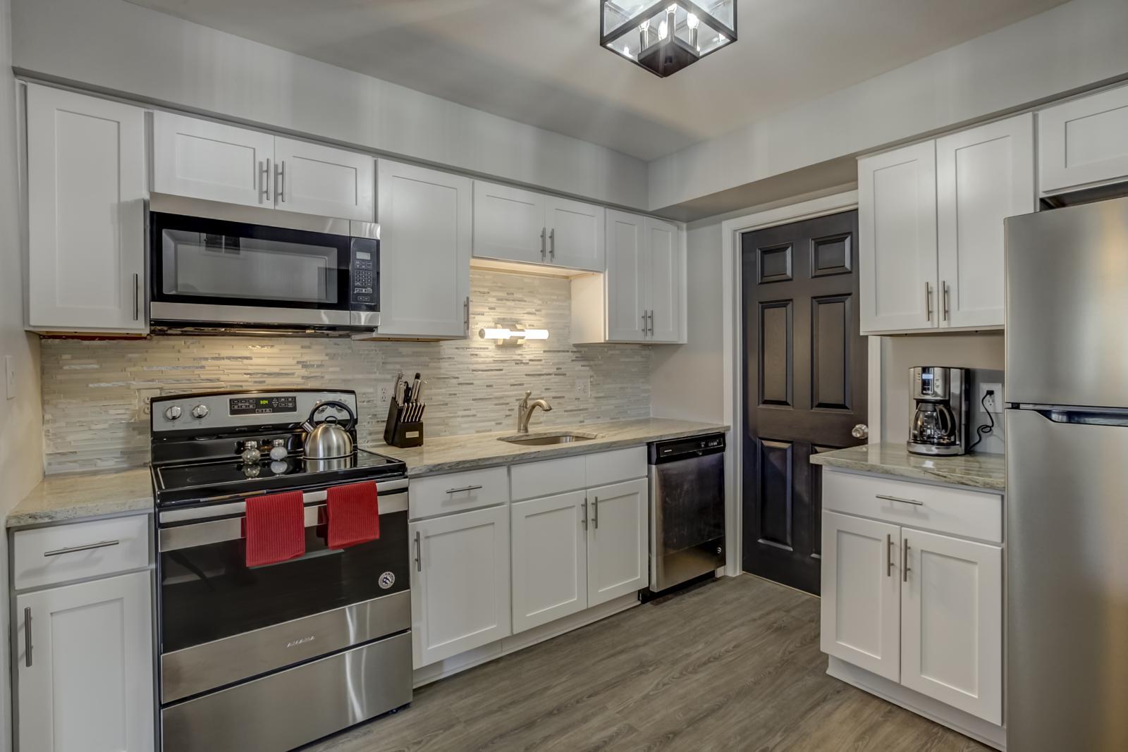 Kitchen with white shaker cabinets, glass tile backsplash, undermount sink and a stainless steel electric range