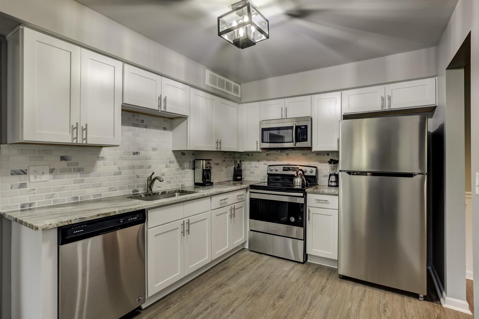 Kitchen with white shaker cabinets, granite countertops, marble subway backsplash and stainless steel appliances