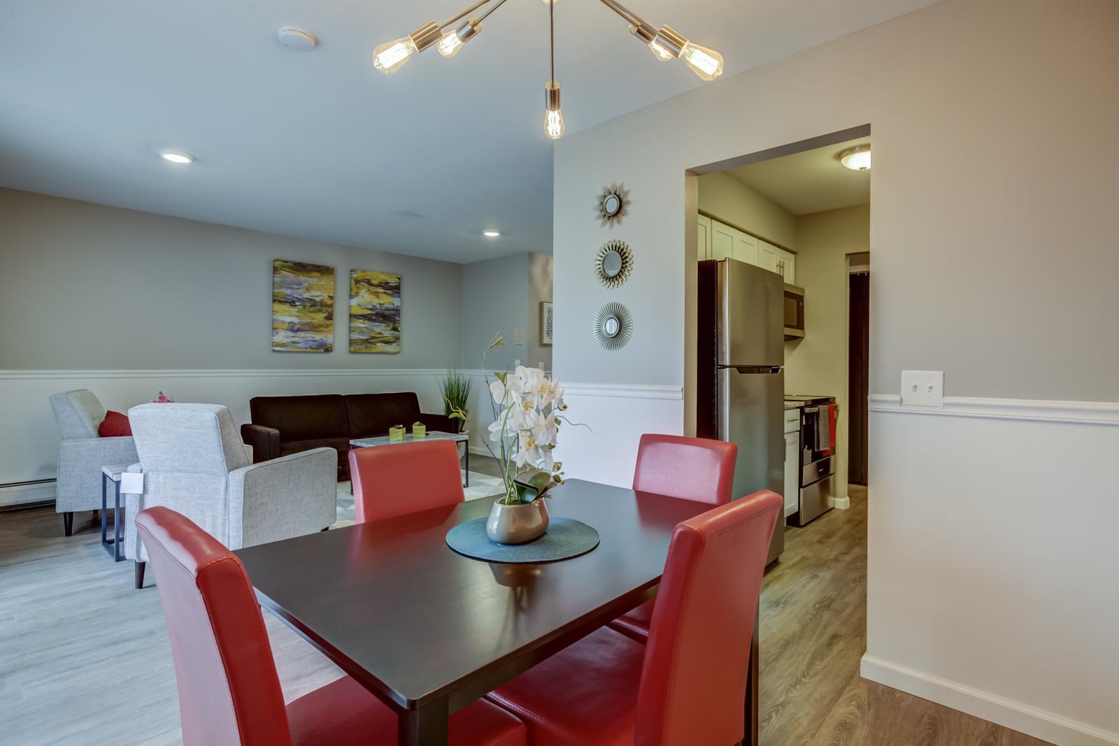 Dining area with red chairs and a modern light fixture, open to the living room and the kitchen