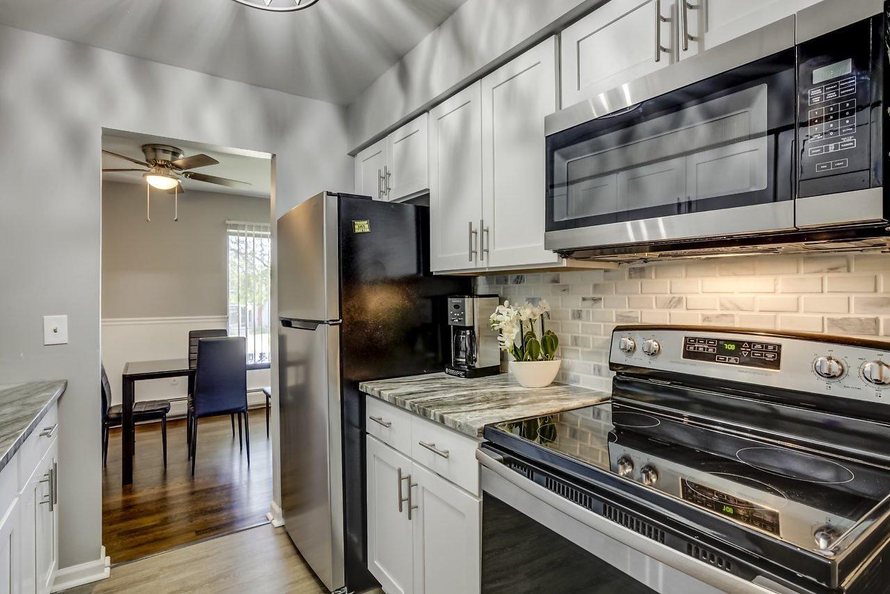 Z on Kingslane renovated kitchen with white shaker cabinets, stone counters and stainless appliances