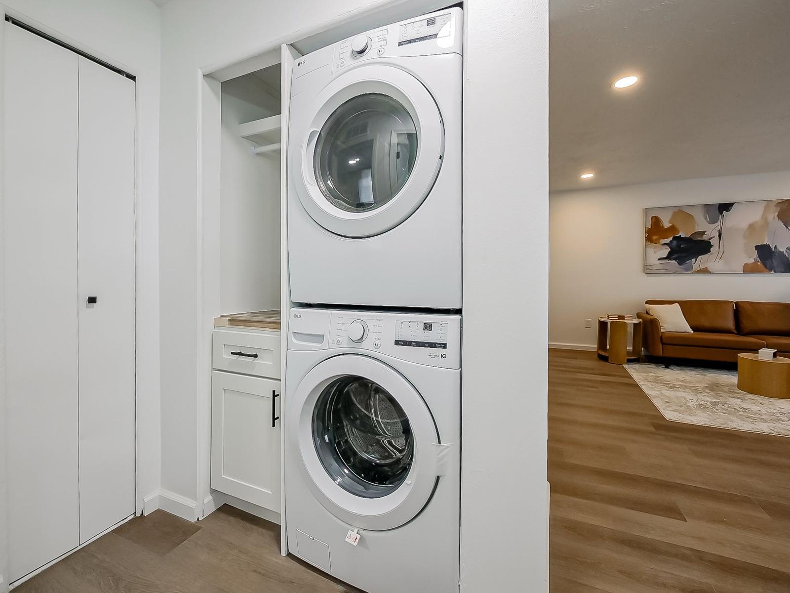 Full-size stacked LG washer and dryer in a laundry closet beside the living room